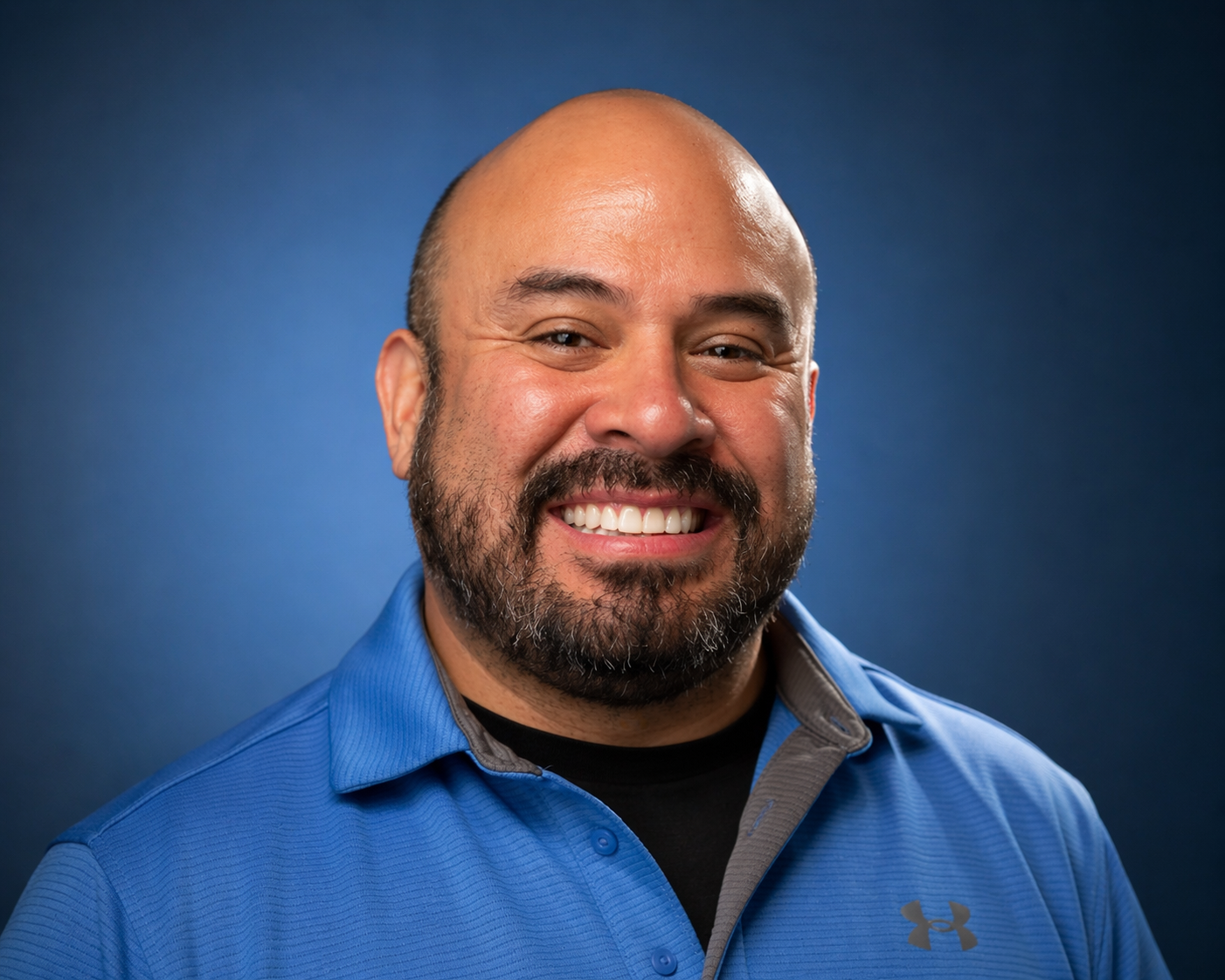 Professional headshot of David Evans smiling in a blue polo against a dark studio background